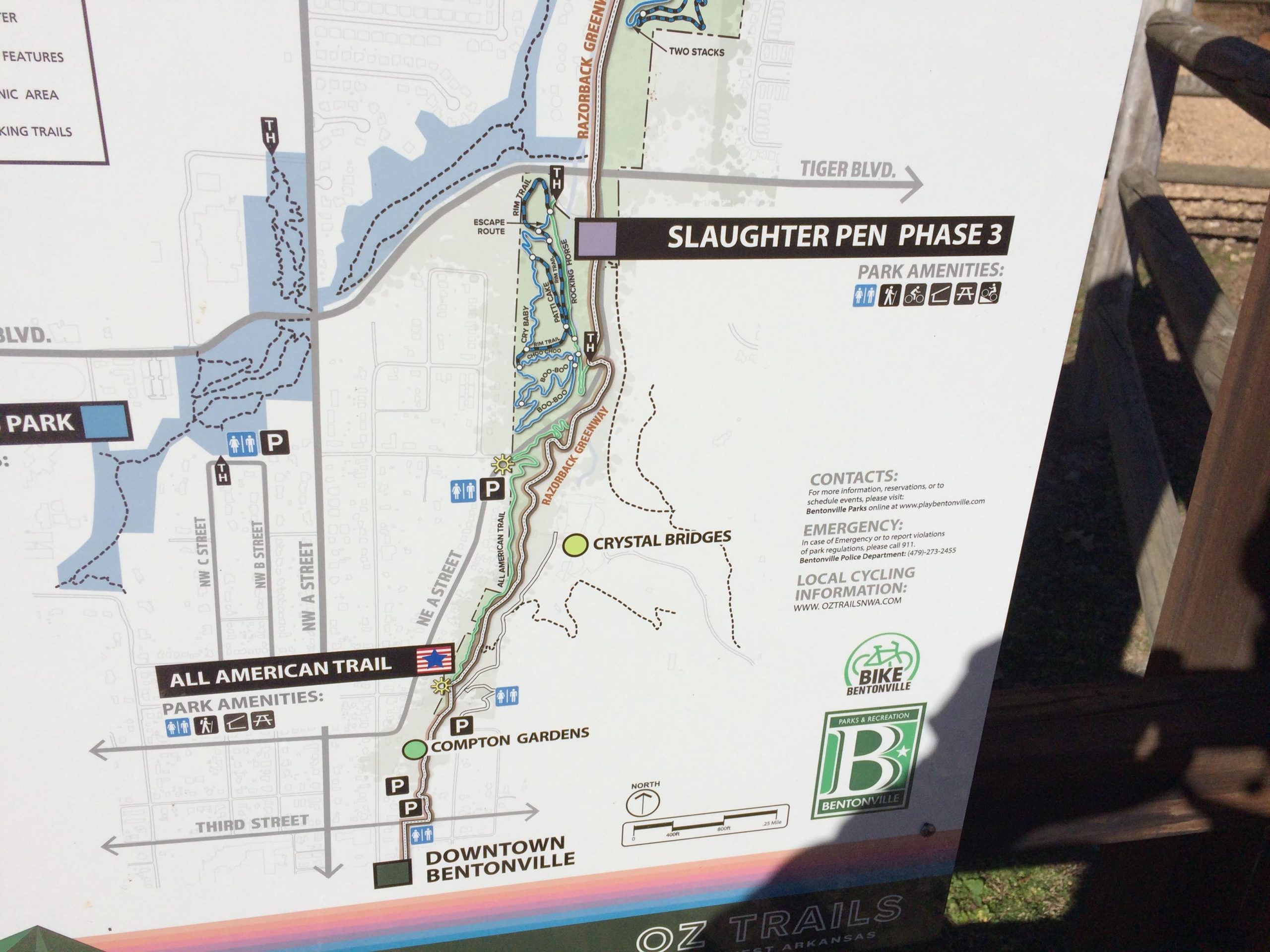Map of Slaughter Pen Phase 3 in Bentonville, Arkansas, showing nearby trails, park amenities, and contact information for local cycling. Features include routes for biking and walking, parking areas, and connections to downtown Bentonville and Crystal Bridges. Slaughter Pen Trail mountain bike trail.