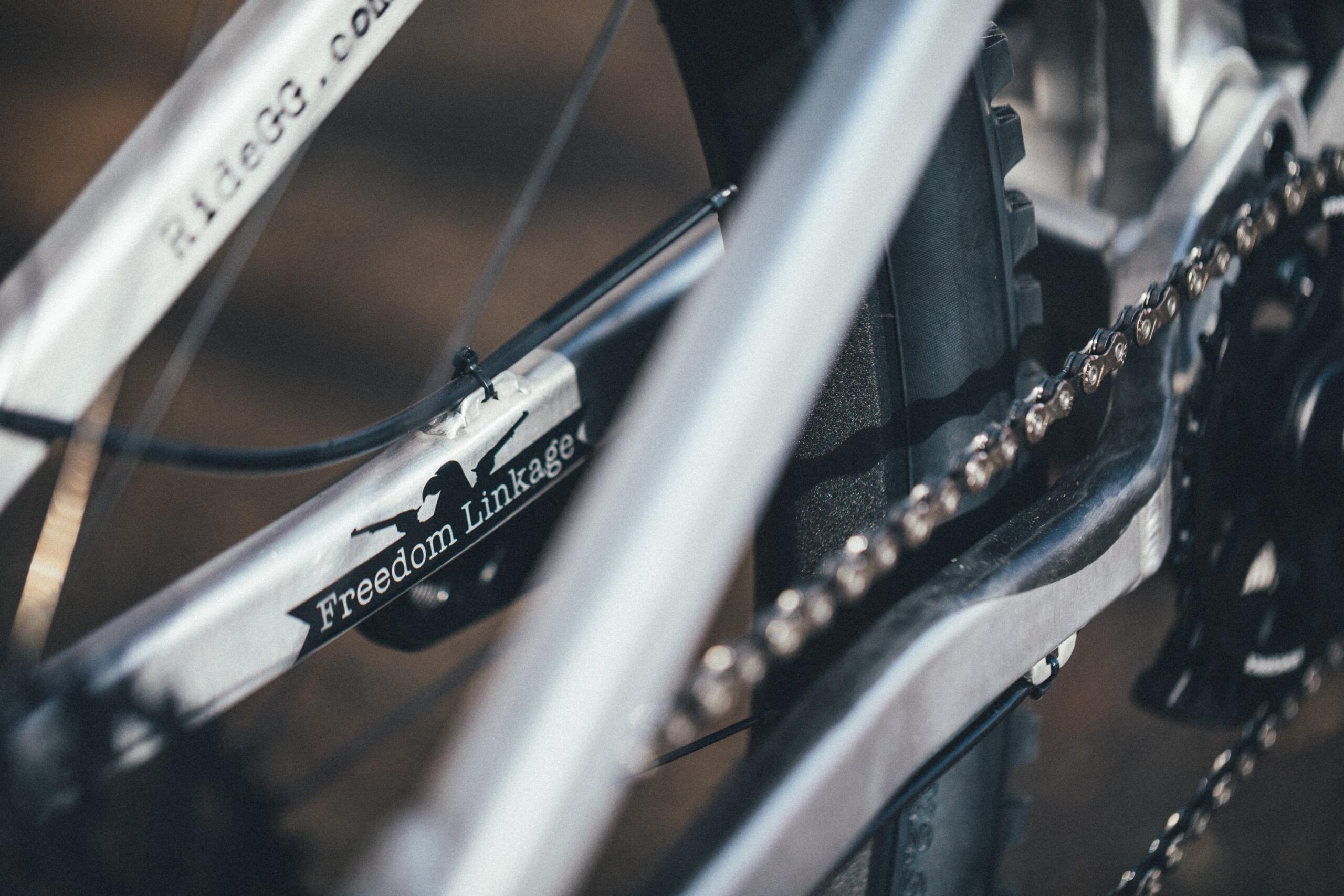 Guerrilla Gravity Megatrail: Close-up view of a bicycle's frame and drivetrain, featuring a "Freedom Linkage" label. The image highlights the chain and gears, showcasing the intricate mechanics of the bike.