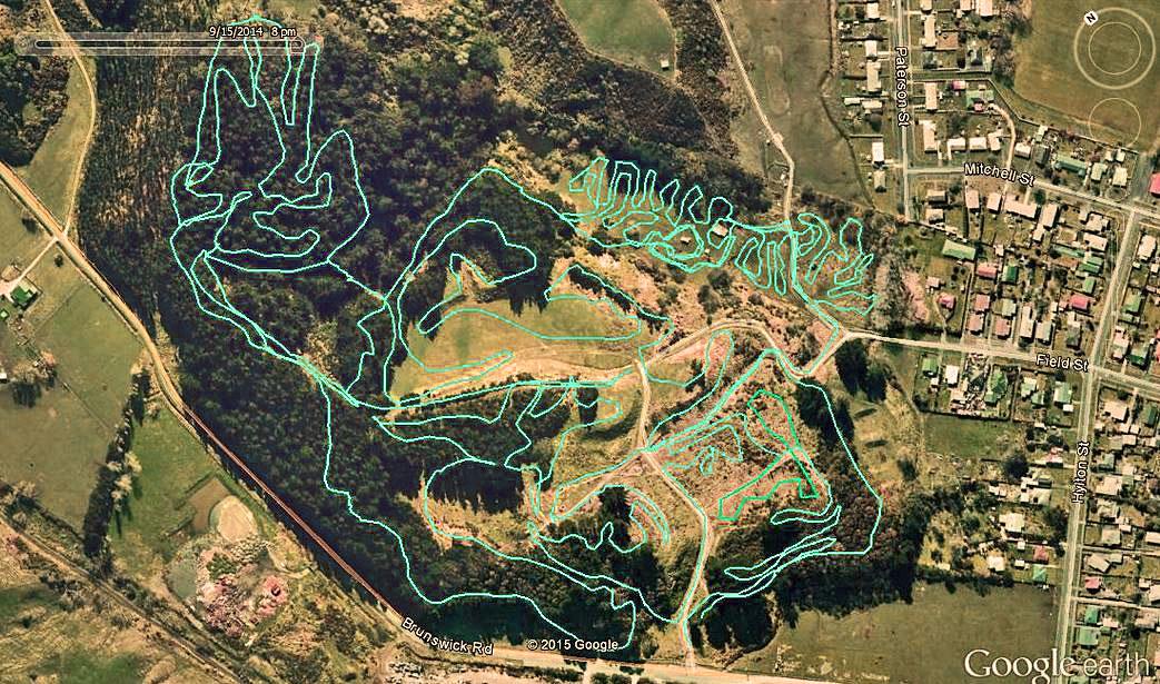 Aerial view of a landscape with overlaid map lines depicting trails and pathways, surrounded by greenery and nearby residential areas. The map features contours and paths that create intricate shapes across the terrain. Hylton Park mountain bike trail.