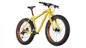 Salsa Mukluk: A bright yellow fat bike with large, wide tires featuring orange rims, designed for off-road biking. The bike has a sleek frame, a comfortable seat, and handlebars suitable for rugged terrain.