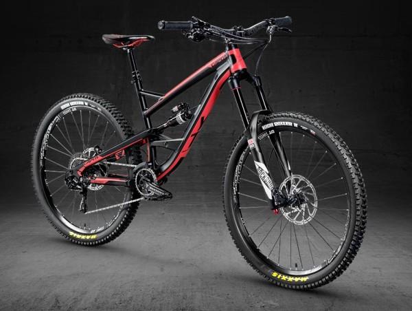 YT Capra: A sleek red and black mountain bike positioned against a dark background, showcasing its lightweight frame, thick tires, and front suspension fork. The bike features disc brakes and modern handlebars, highlighting its design for off-road cycling.
