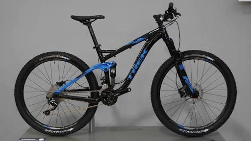 Trek Fuel EX 7 29er: A black and blue mountain bike displayed against a neutral background, showcasing its front and side profile. The bike features sturdy tires, a suspension frame, and a modern design suitable for off-road riding.