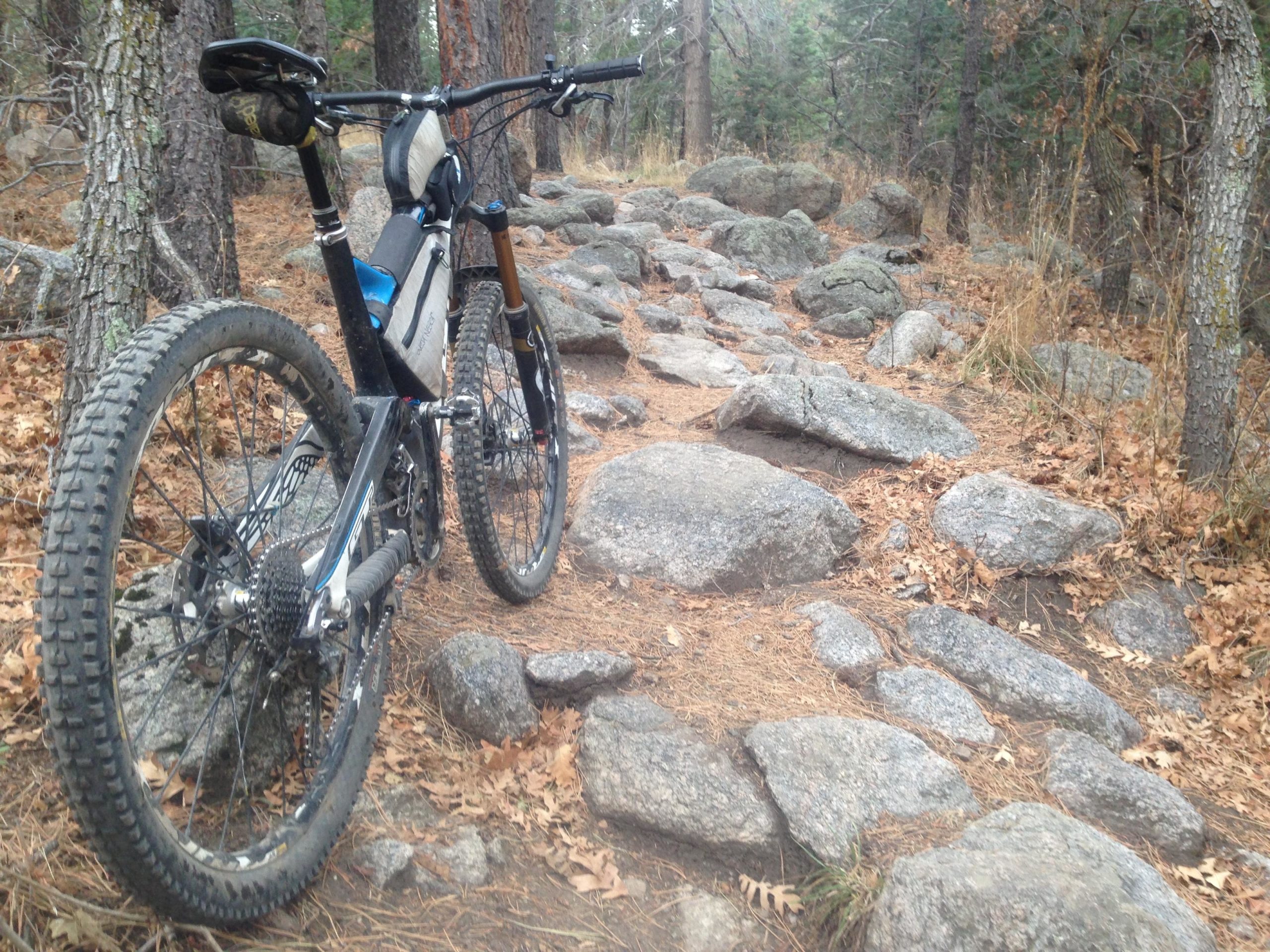 Mountain bike parked on a rocky trail surrounded by trees and fallen leaves. Cheyenne Mountain State Park mountain bike trail.