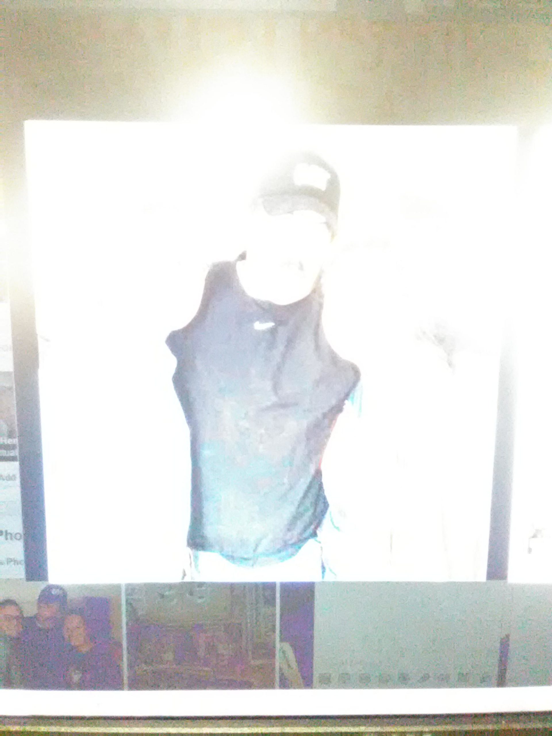 A partially illuminated figure wearing a black sleeveless shirt and a cap stands in front of a bright background, creating a glare. The image appears to be captured from a screen, with additional photos visible in a collage format at the bottom. Pemberton Loop mountain bike trail.