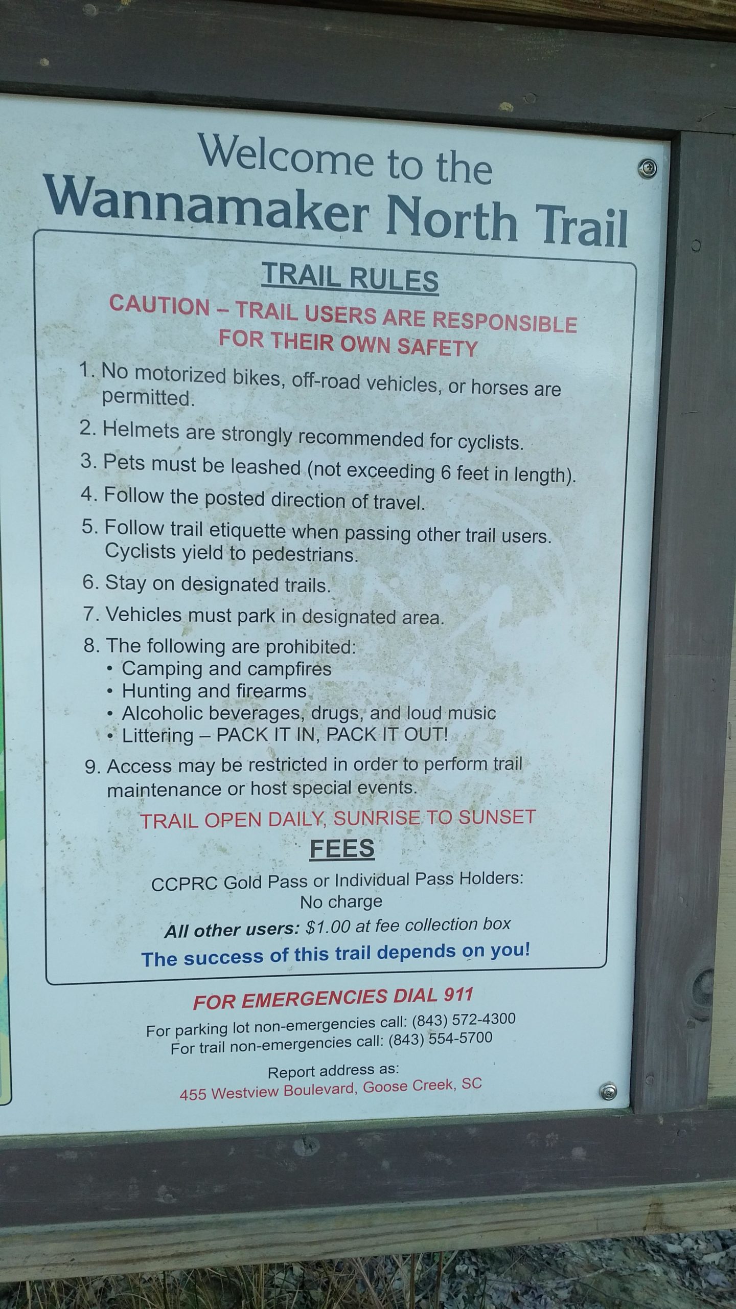 Welcome sign for the Wannamaker North Trail displaying trail rules, safety advisories, and fee information. The sign includes essential guidelines for users, such as no motorized vehicles allowed, pet leash requirements, and prohibited activities like camping and alcohol. It also provides emergency contact numbers and specifies that the trail is open daily from sunrise to sunset. Wannamaker Park mountain bike trail.