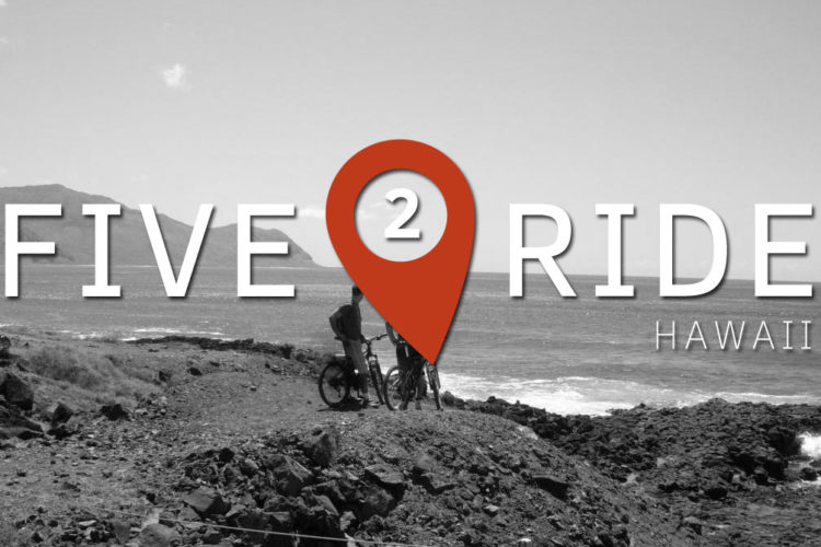 Alt text: A black-and-white image featuring two cyclists with bicycles, overlooking the ocean and mountains in Hawaii. The text "FIVE 2 RIDE HAWAII" is prominently displayed, with a red map marker icon integrated into the design.