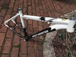 Rocky Mountain Vertex 50: A white and black mountain bike frame resting on a brick surface. The frame features the brand name "Rocky Mountain" prominently displayed.
