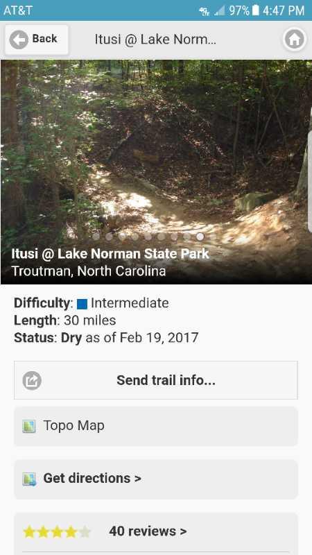 A trail at Lake Norman State Park in Troutman, North Carolina, featuring a dirt path through a wooded area. The trail is marked as intermediate difficulty, with a length of 30 miles and a dry status as of February 19, 2017. Bent Creek mountain bike trail.