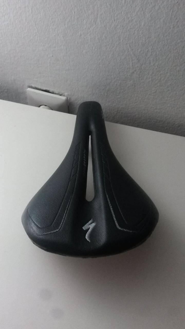 Trek Remedy 8: Black bicycle saddle with a distinctive design, featuring a central cutout for comfort and the logo of a bike brand. The saddle is placed on a light-colored surface with a plain background.