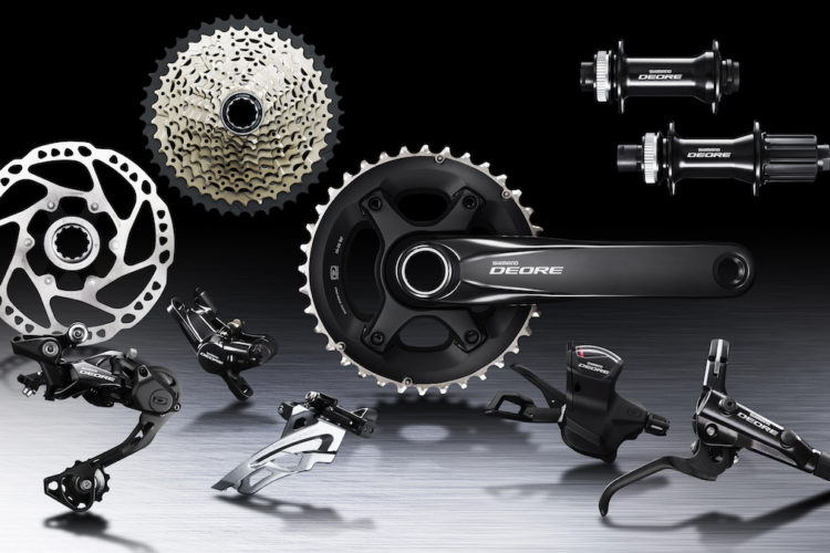 Alt text: A collection of bicycle components featuring Shimano Deore products, including a crankset, derailleur, cassette, disc brake, and shifters, arranged on a sleek background.