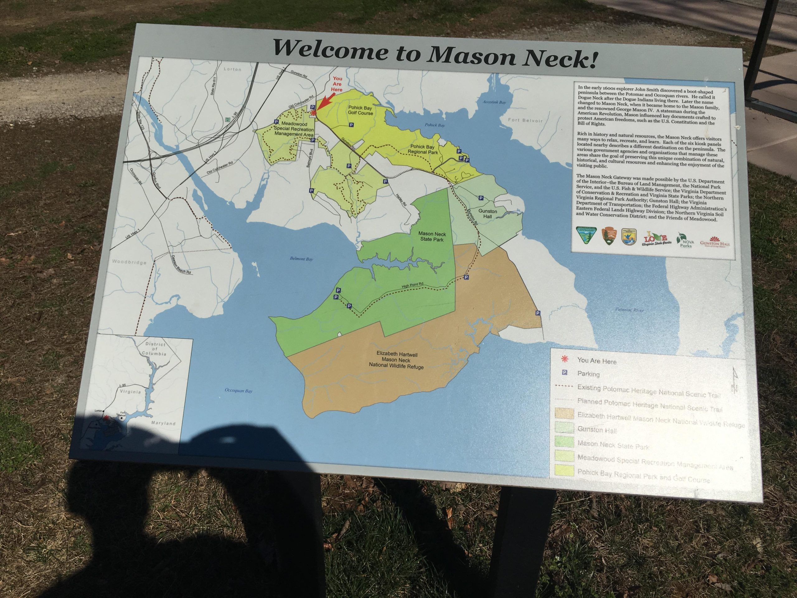 A map displaying the layout of Mason Neck, highlighting parks, trails, and nearby features such as the Potomac Heritage National Scenic Trail. The map includes a "You Are Here" indicator, showing the current location, and outlines nearby attractions including Elizabeth Hartwell Mason Neck National Wildlife Refuge, Mason Neck State Park, and Pohick Bay Regional Park and Golf Course. The area is depicted in a variety of colors representing different land designations and features, along with informational text about the history and significance of the region. Meadowood mountain bike trail.
