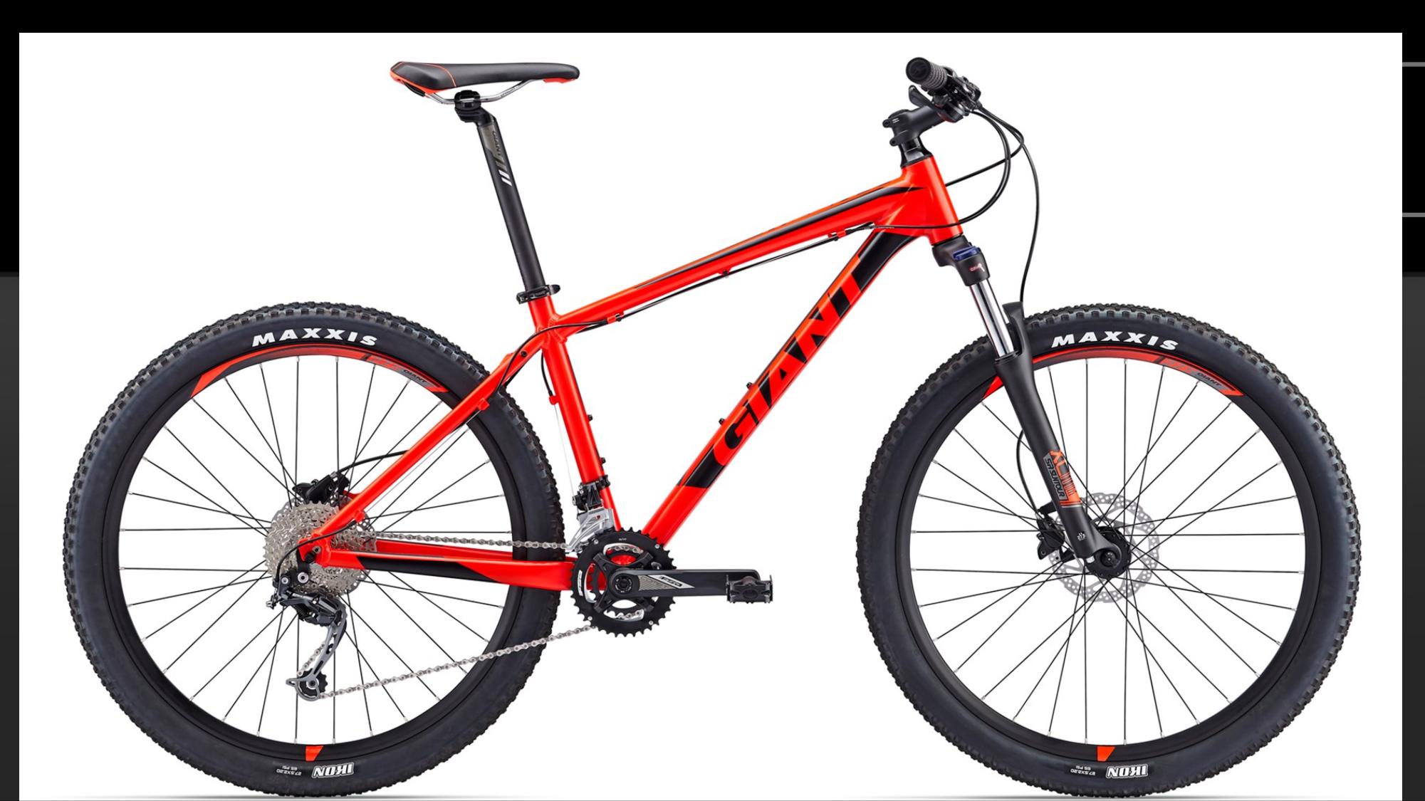 Giant Talon 27.5 2: A red mountain bike with a lightweight frame, featuring wide tires with Maxxis branding, a front suspension fork, and disc brakes. The bike displays a prominent "Giant" logo on the frame, showcasing a sporty design suitable for off-road riding.