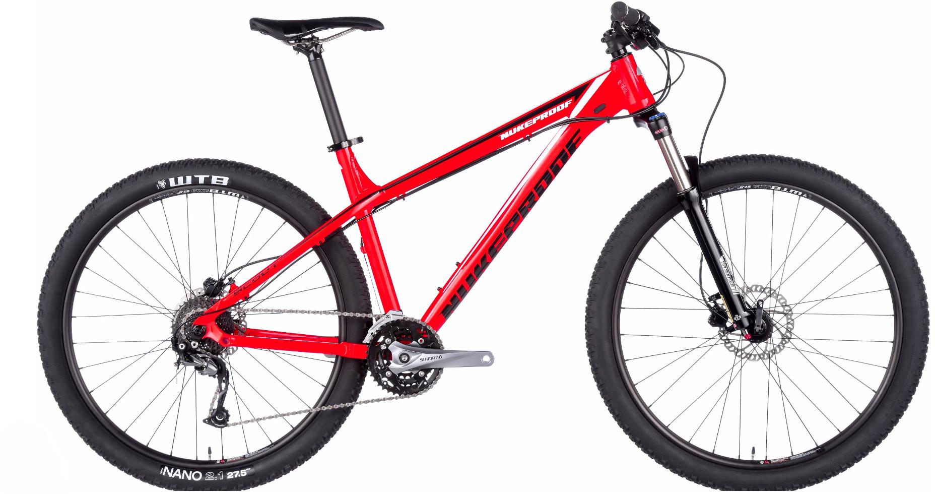Nukeproof Scout: A bright red mountain bike with a lightweight frame and wide tires, featuring a front suspension fork, disc brakes, and Shimano components. The bike is positioned against a plain background, showcasing its design and features.