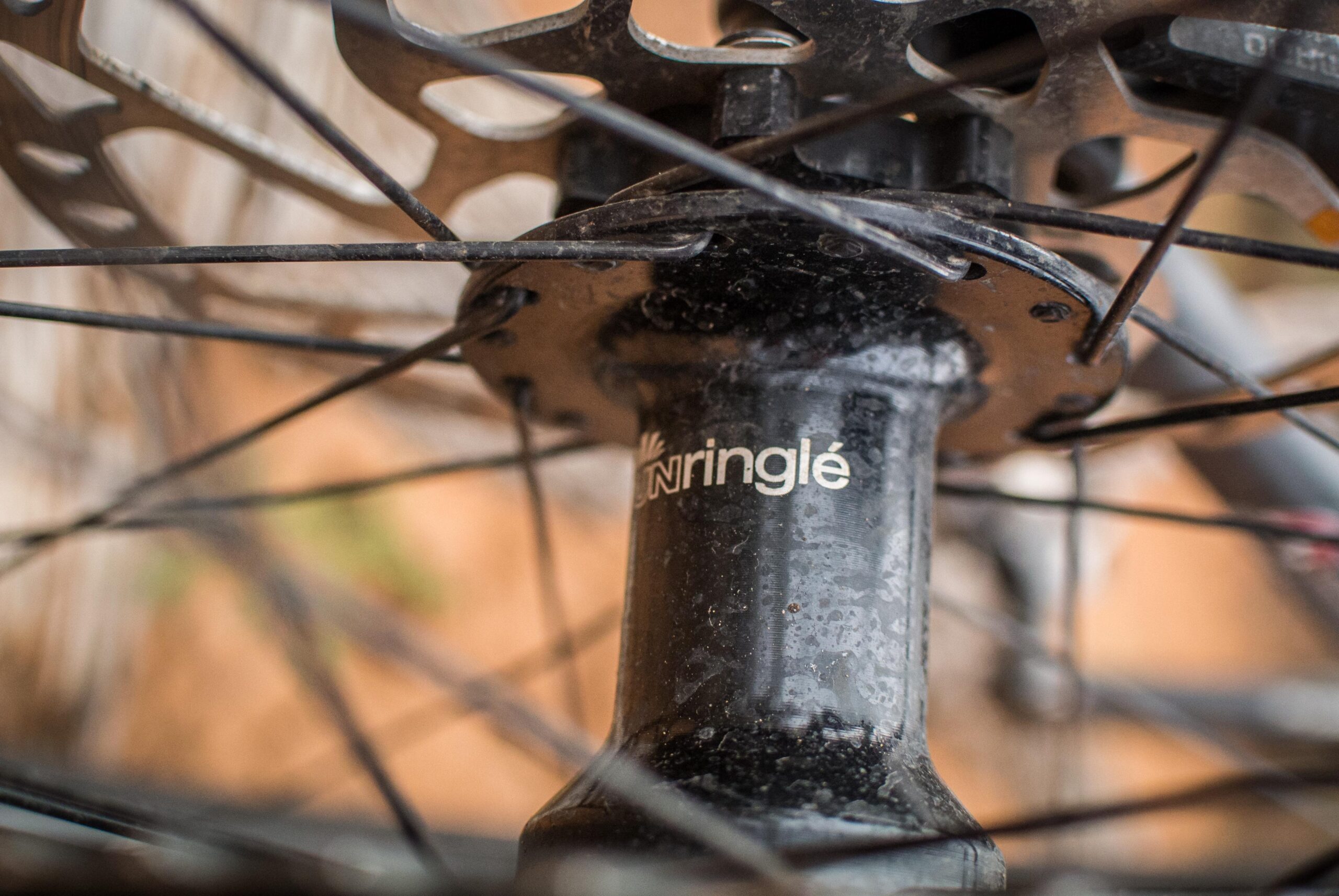 Rocky Mountain Pipeline: Close-up image of a bicycle wheel hub with visible spokes and a brand logo, showing signs of wear. The background is blurred, highlighting the intricate details of the hub's design.