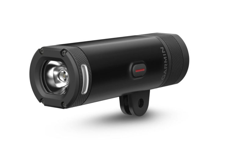 A black Garmin bike light with a cylindrical design, featuring a front lens, a red power button, and textured grips on both ends. The light is mounted on a bracket for attachment to a bicycle.