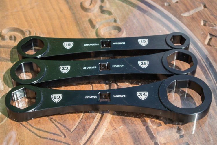 Three black wrenches of varying sizes displayed on a wooden surface. The wrenches are labeled with their corresponding sizes: 15, 23, 25, and 34. They appear to be designed for specific applications, possibly related to bike maintenance or repairs.