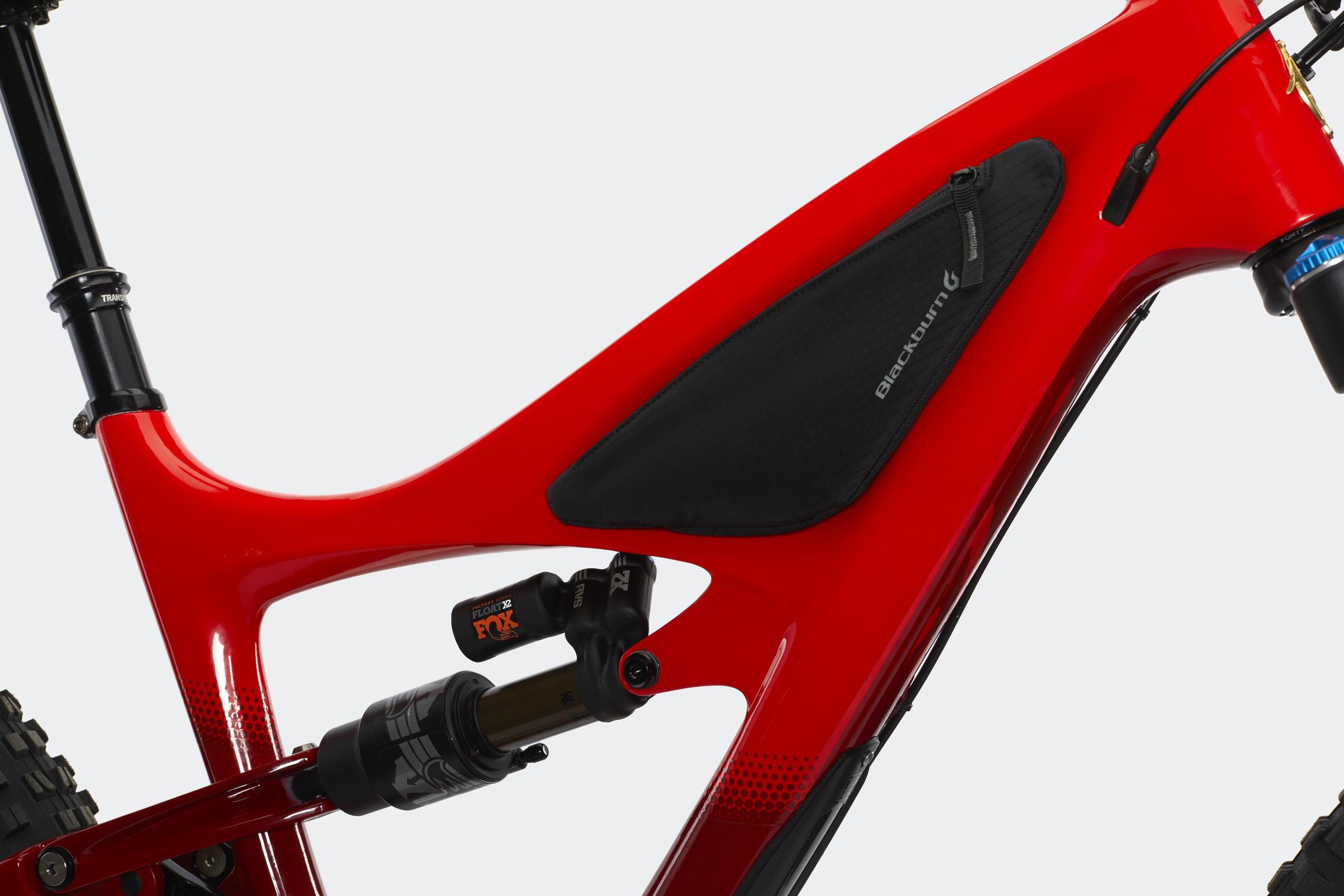 Ibis Mojo HD4: Close-up of a red mountain bike frame featuring a black Blackburn storage bag positioned on the side. The suspension components and cable routing are visible, highlighting the bike's design and technical features.