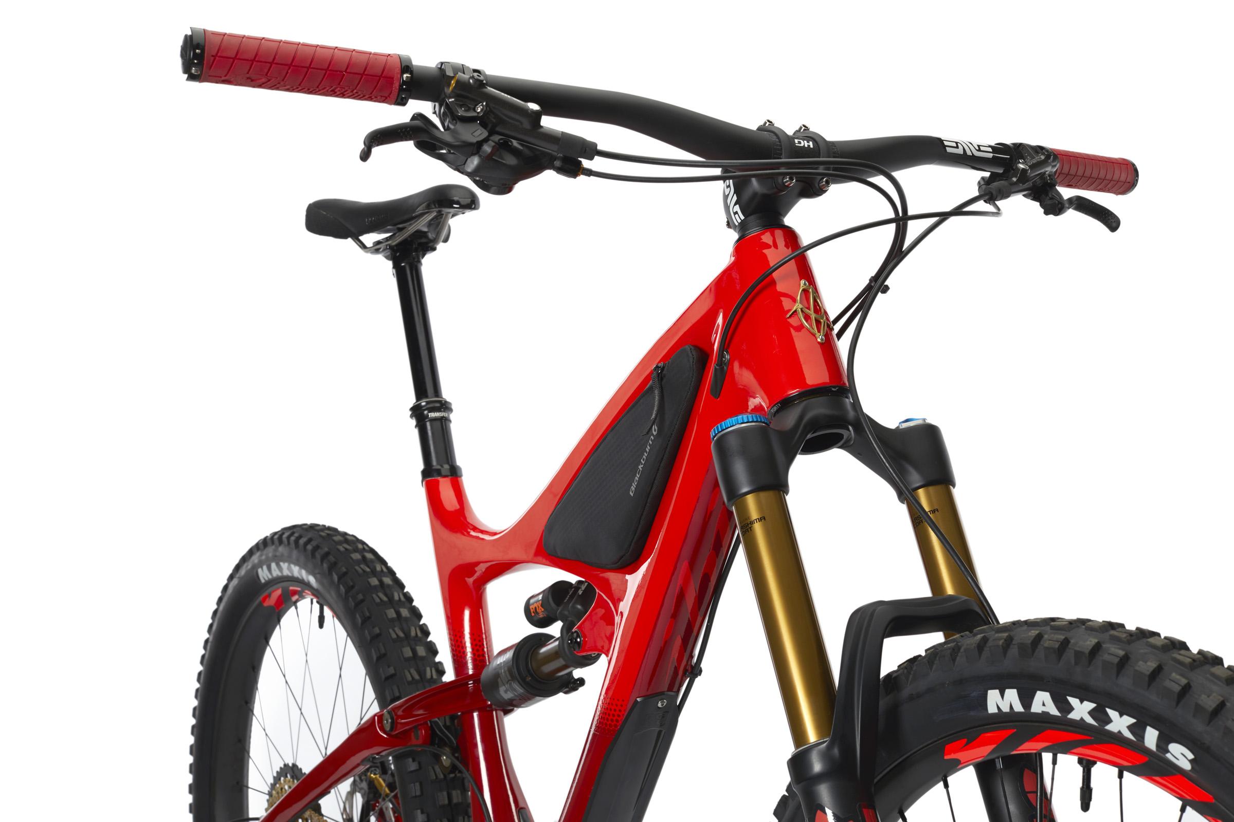 Ibis Mojo HD4: Image of a modern mountain bike, featuring a vibrant red frame, black handlebars with red grips, and a prominent suspension fork with gold components. The bike is equipped with high-quality tires marked 'MAXXIS.' It is positioned against a plain white background, showcasing its sleek design and features.