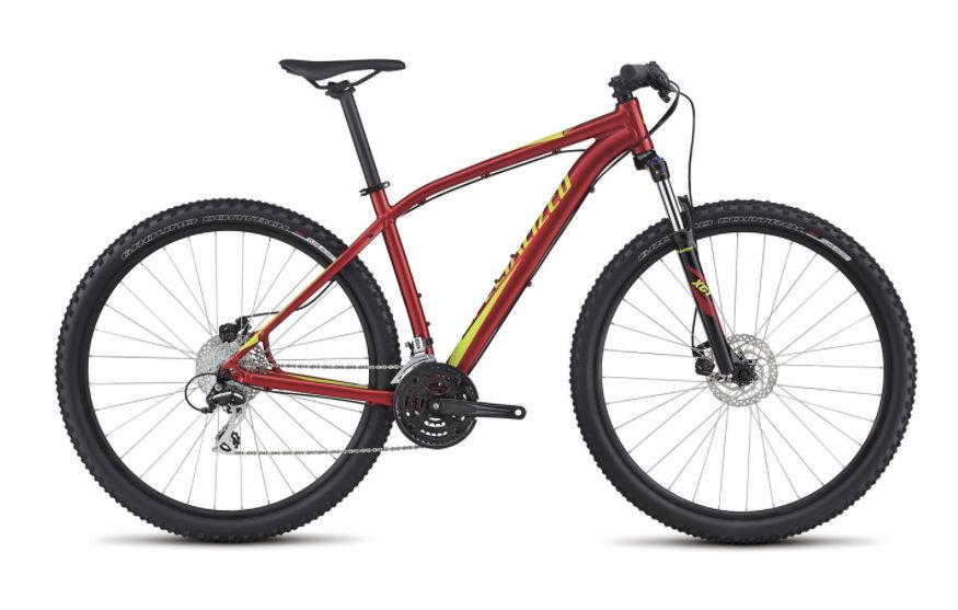 Specialized Rockhopper: A red and yellow mountain bike with disc brakes, thick tires, and a lightweight frame, positioned on a plain white background. The bike features a traditional hardtail design, a prominent gear system, and is designed for off-road performance.