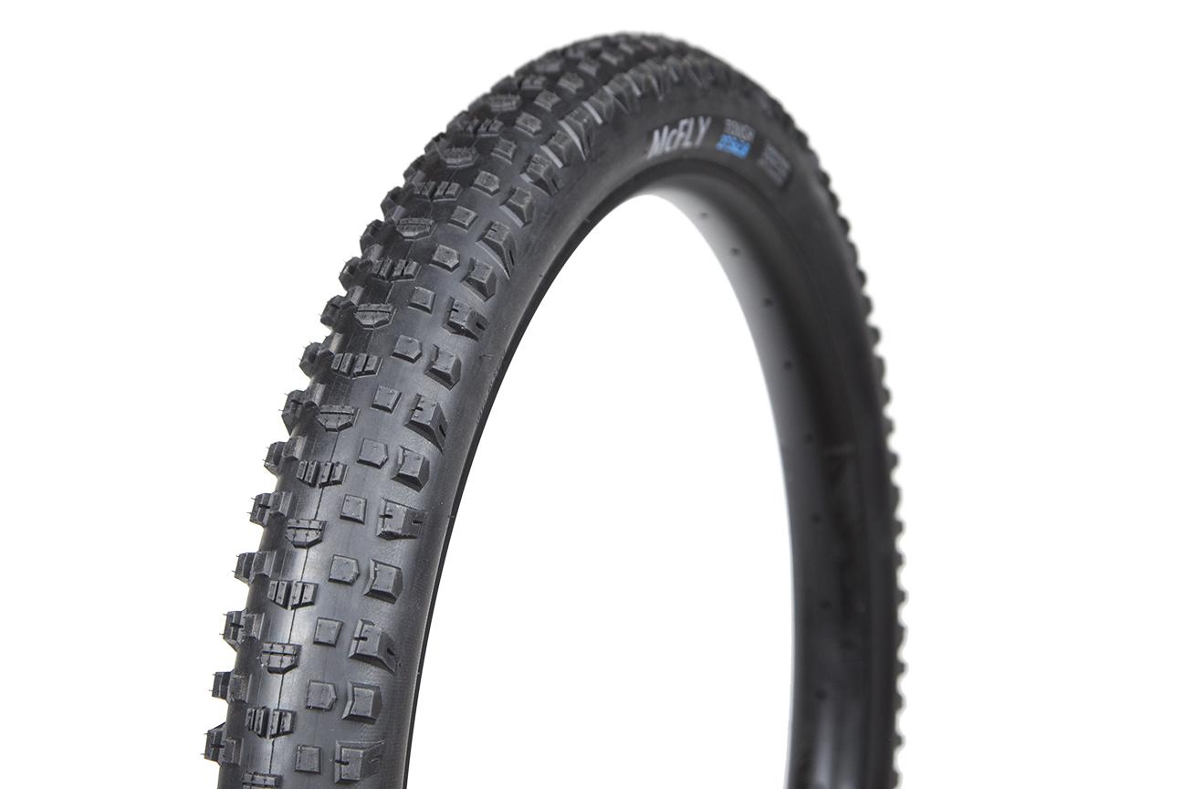 Terrene McFly: A close-up of a black mountain bike tire featuring a knobby tread pattern designed for traction on rough terrain. The sidewall displays branding and specifications.