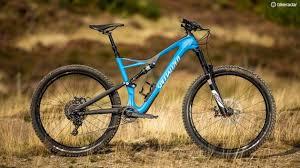 Specialized Stumpjumper Comp Carbon 29: A blue mountain bike positioned on a grassy outdoor terrain, showcasing its sturdy frame and thick tires.