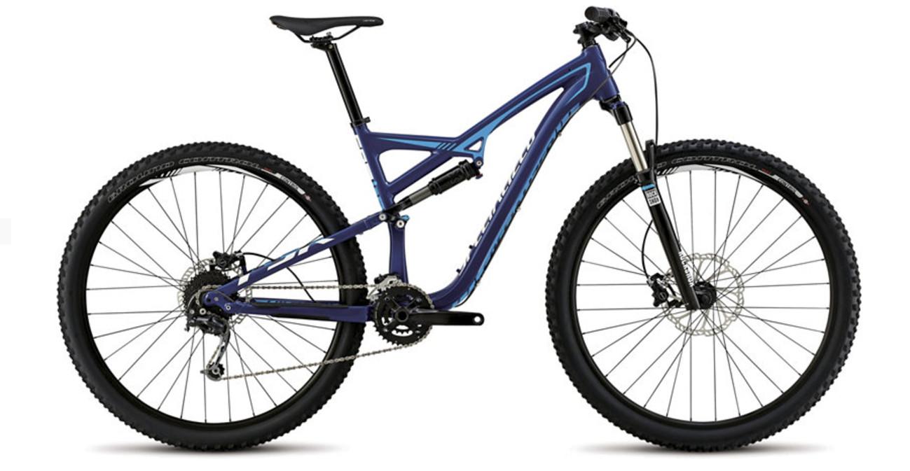 Specialized Camber 29: A blue and black mountain bike with a full suspension system, wide tires, and disc brakes, positioned on a white background. The bike features a lightweight frame design and multiple gears, suitable for off-road cycling.