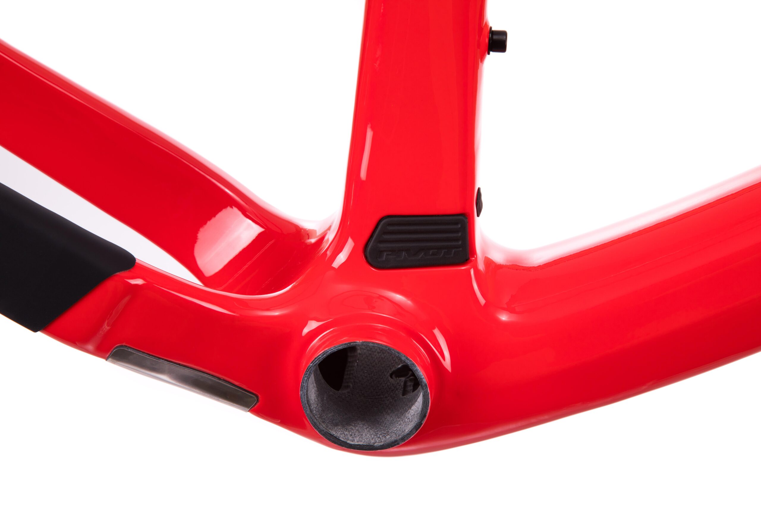 Pivot LES 27.5: Close-up view of a red bicycle frame, highlighting the bottom bracket area and sleek, aerodynamic design features. The frame exhibits a glossy finish with a visible brand label and black protective components.