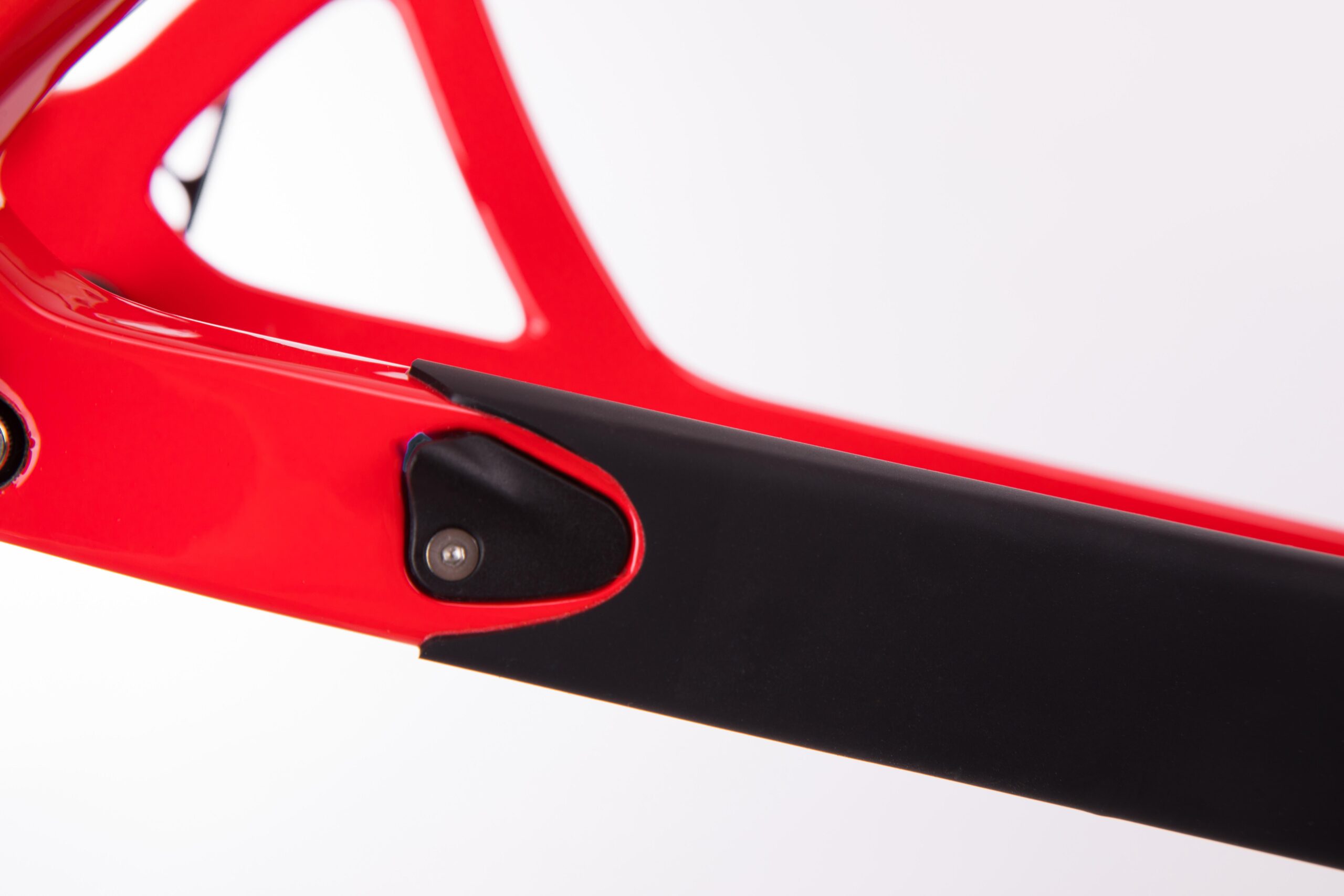 Pivot LES 27.5: Close-up of a bright red bicycle frame featuring a black protective guard at the rear. The image highlights the sleek design and detailing of the frame, with a focus on the junction where the black guard meets the red structure. The background is plain white, emphasizing the colors and materials of the bike frame.