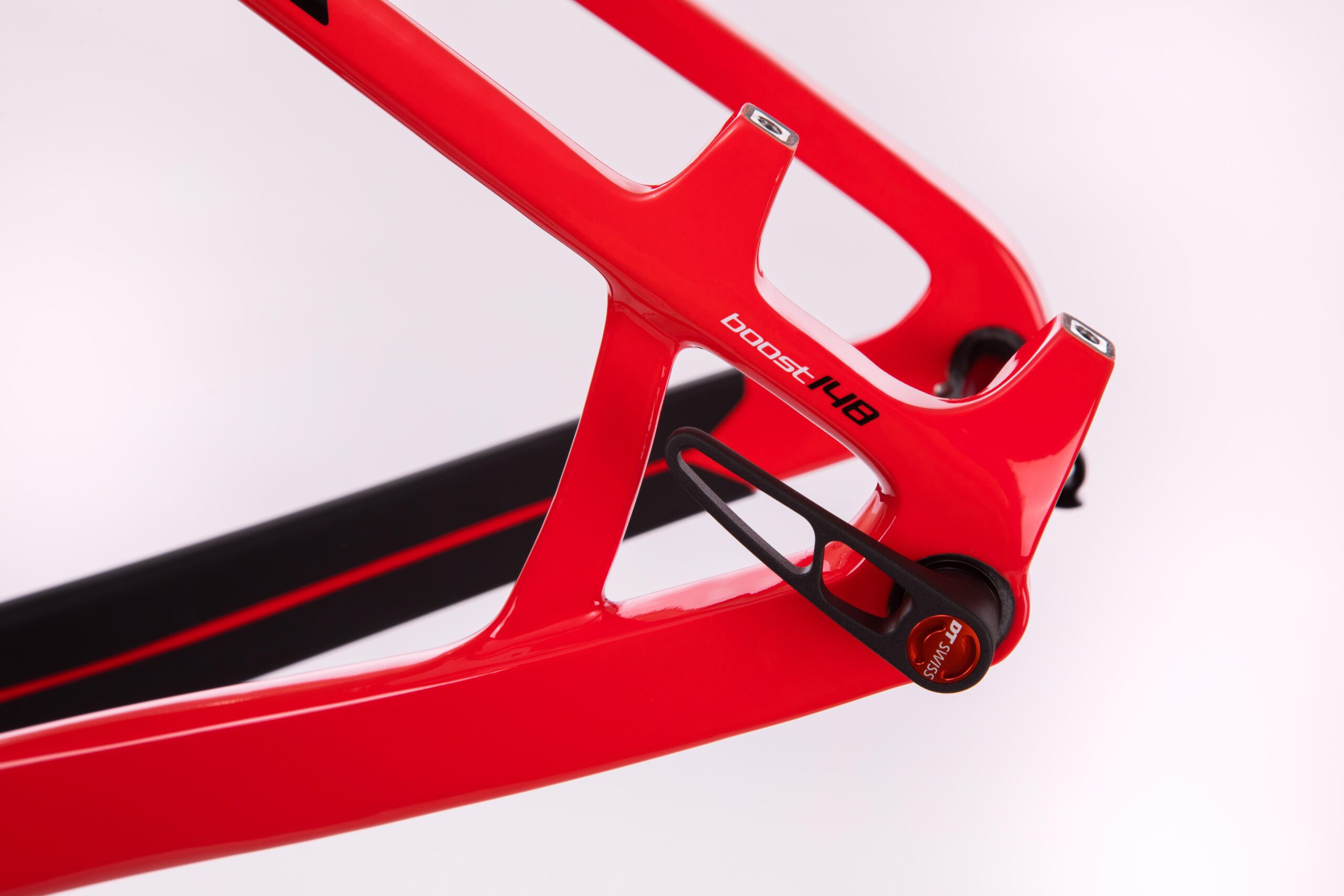 Pivot LES 27.5: Close-up of a sleek red bicycle frame showcasing the "boost 148" branding and a black component, highlighting the frame's design and construction details against a soft gradient background.