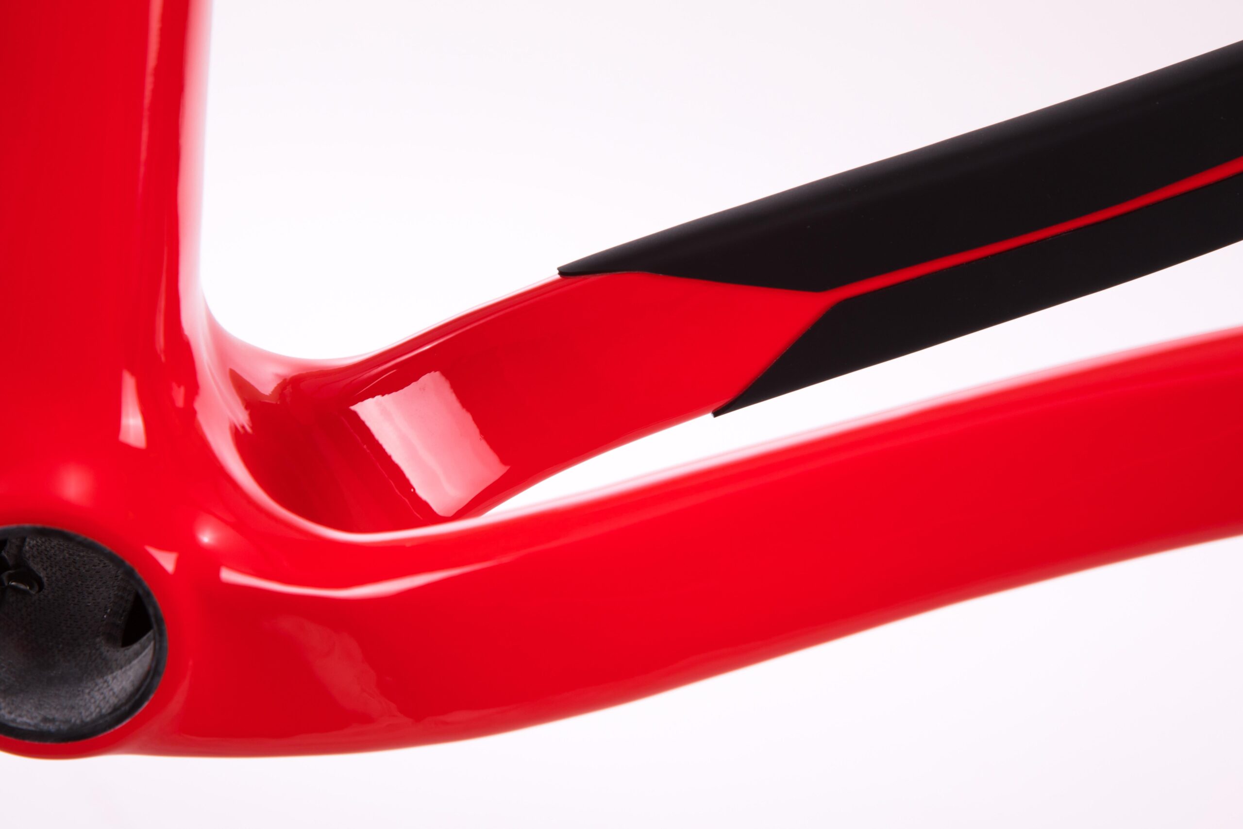 Pivot LES 27.5: Close-up view of a red bicycle frame, showcasing its sleek design and glossy finish. The image highlights the curved lines and a contrasting black section, emphasizing the modern aesthetic and craftsmanship of the bike's construction.