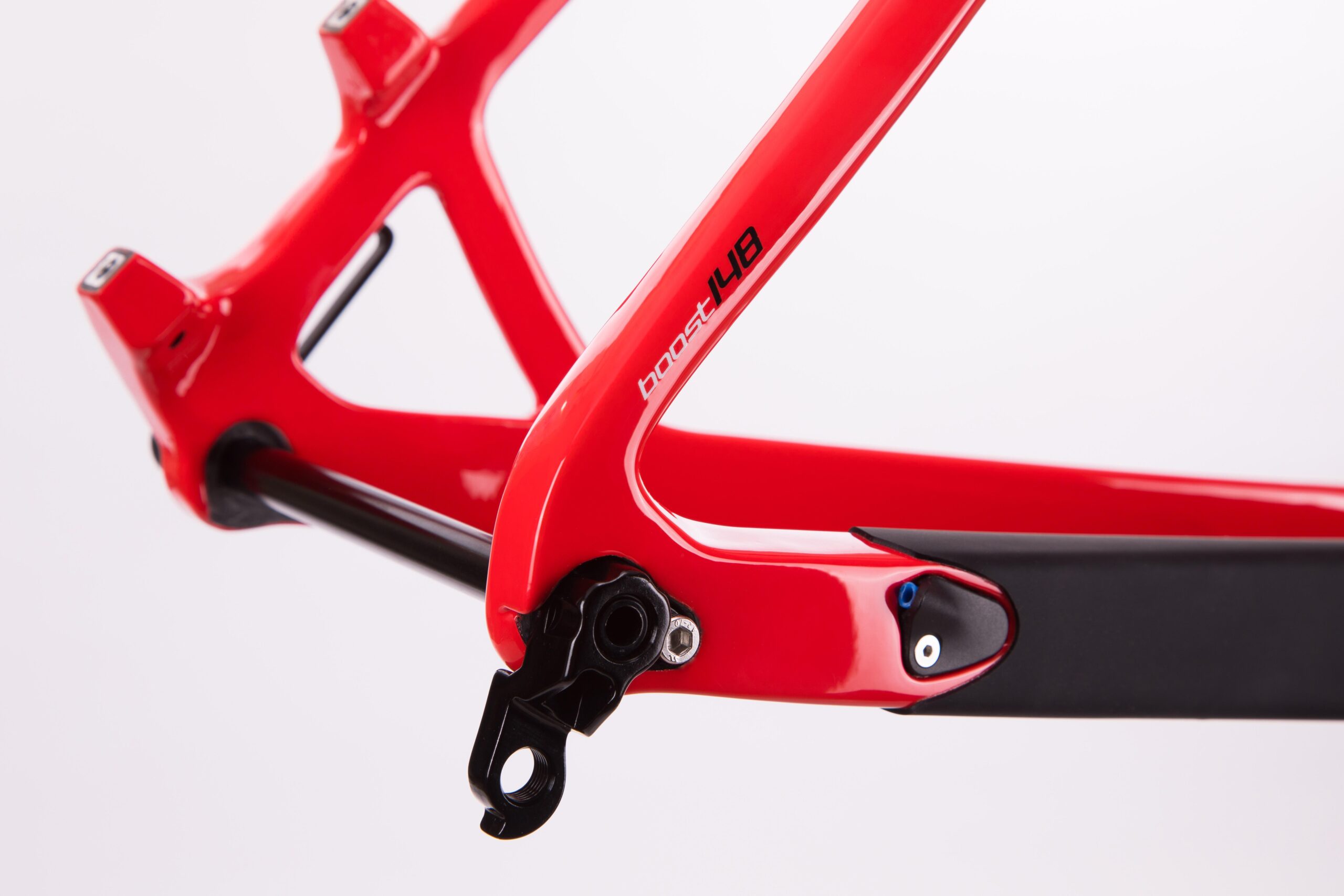Pivot LES 27.5: A close-up image of a bright red bicycle frame, showcasing its sleek design and features. The frame includes a black section and is labeled with "boost 148," highlighting modern engineering elements. The background is plain white, emphasizing the frame's details.