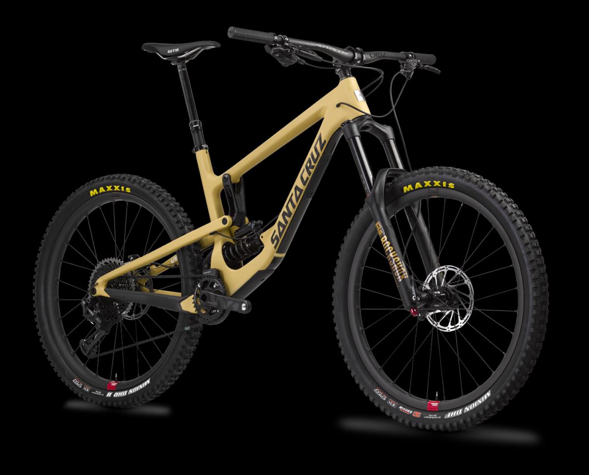 Santa Cruz Nomad: A modern mountain bike featuring a sleek design with a matte tan frame, black components, and oversized wheels. The bike includes disc brakes and high-traction tires, showcasing branding from Santa Cruz and Maxxis. It is presented against a solid black background, emphasizing its features.