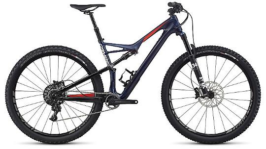 Specialized Camber Expert Carbon 29: Mountain bike with a sleek, dark frame and red accents, featuring wide tires and disc brakes. The bike is positioned to showcase its suspension system and gear components, ideal for off-road cycling.