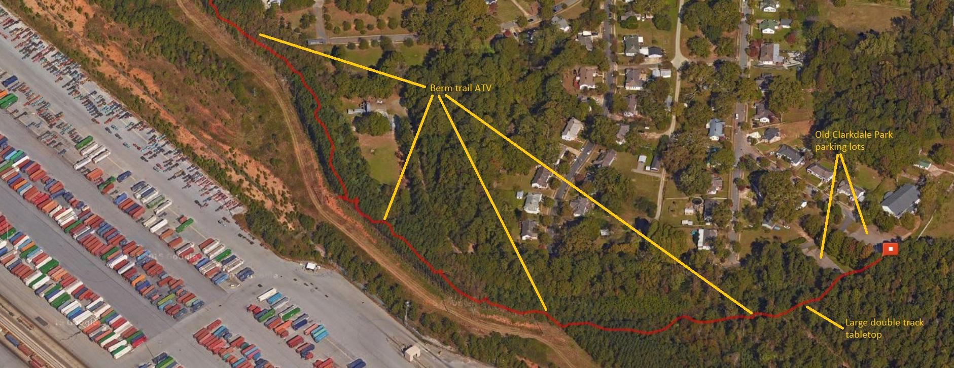 Aerial view of a residential area with outlined paths and trails. The image features a section of a park, a parking lot labeled "Old Clarkdale Park parking lots," and annotations indicating a "Berm trail ATV" and a "large double track tabletop." In the lower part of the image, a shipping container area is visible. Austell Threadmill MTB Park (Closed) mountain bike trail.