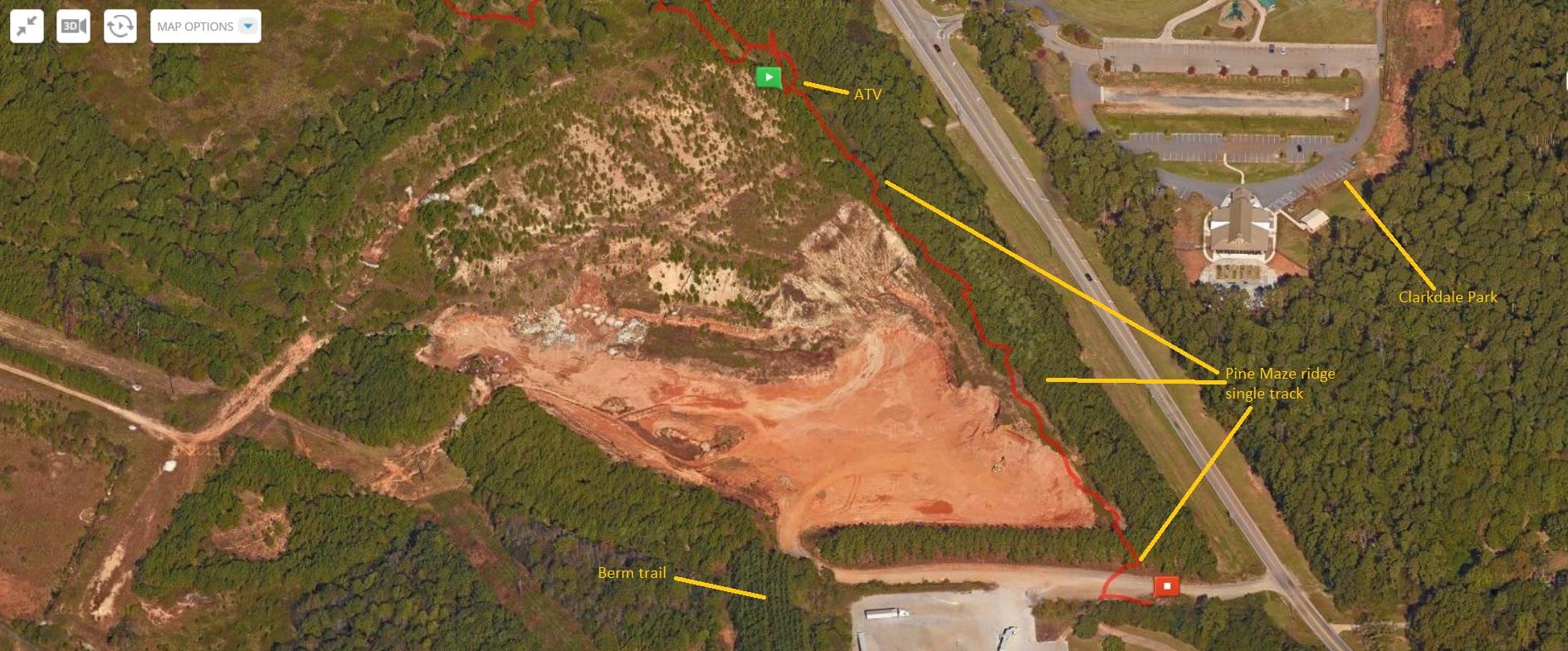 Aerial view map showcasing a wooded area with marked trails and pathways. Key features include Clarkdale Park, an ATV access point, and various trails such as the Pine Maze ridge single track and the Berm trail, indicated with labeled arrows. The surrounding landscape consists of dense greenery and open soil regions, with a road adjacent to the park. Austell Threadmill MTB Park (Closed) mountain bike trail.