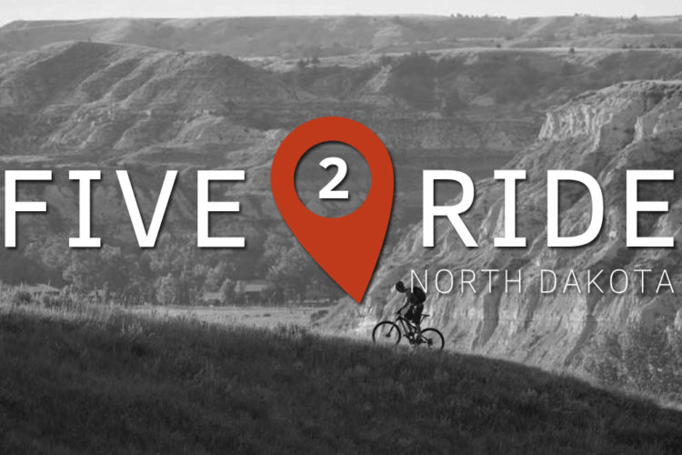 A silhouette of a mountain biker riding along a grassy ridge with layered hills in the background. The image features the text "FIVE 2 RIDE" prominently, accompanied by a location marker icon, and includes the words "NORTH DAKOTA." The overall tone is adventurous and outdoor-focused, set against a black and white landscape.