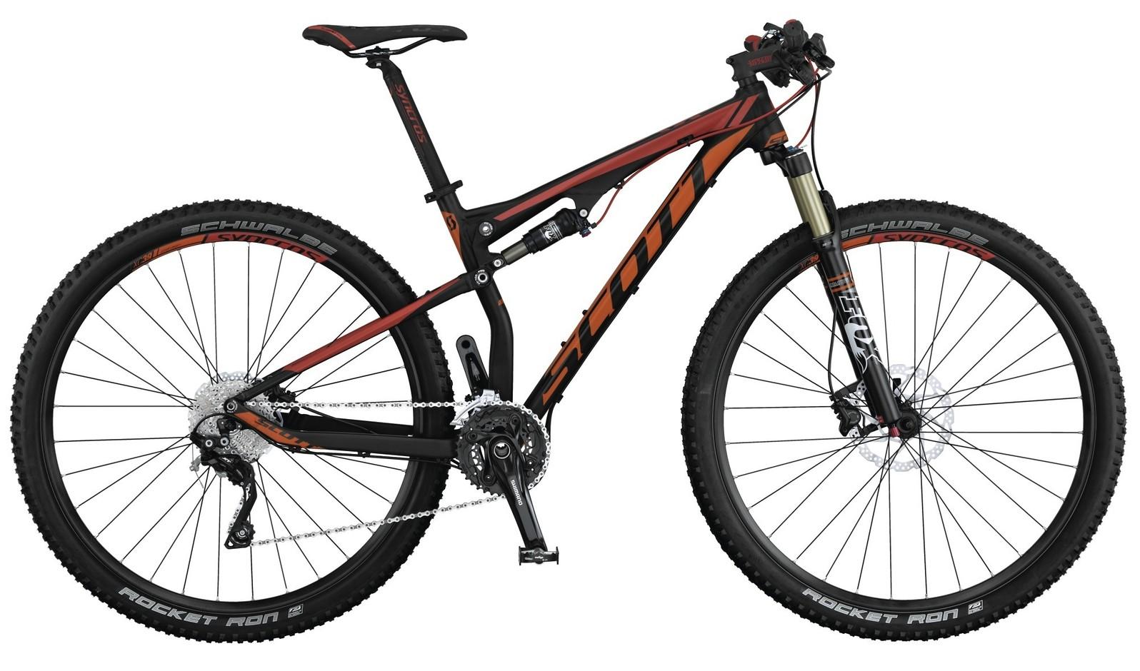 Scott Spark 950: A black and orange mountain bike with full suspension, featuring prominent Schwalbe tires labeled "Rocket Ron," and a detailed drivetrain. The bike has a sleek frame design, a front suspension fork, and is positioned against a plain background.