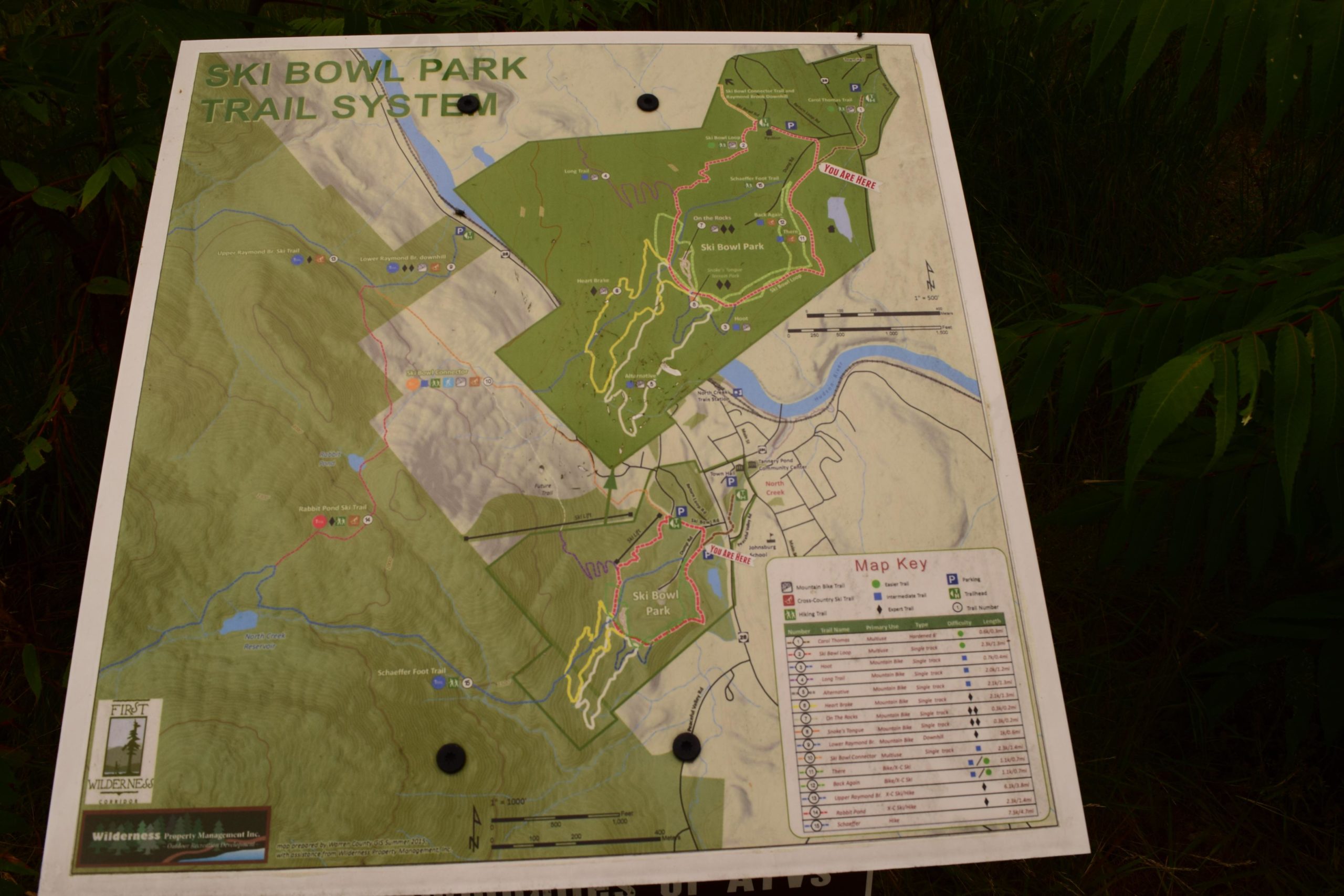 Map of the Ski Bowl Park Trail System, featuring various trails for skiing and hiking, marked with color-coded paths and a map key. The map includes information on trail types, parking locations, and points of interest within the park. A "You Are Here" indicator is present, helping visitors identify their current location. Ski Bowl Park Bike Trails mountain bike trail.