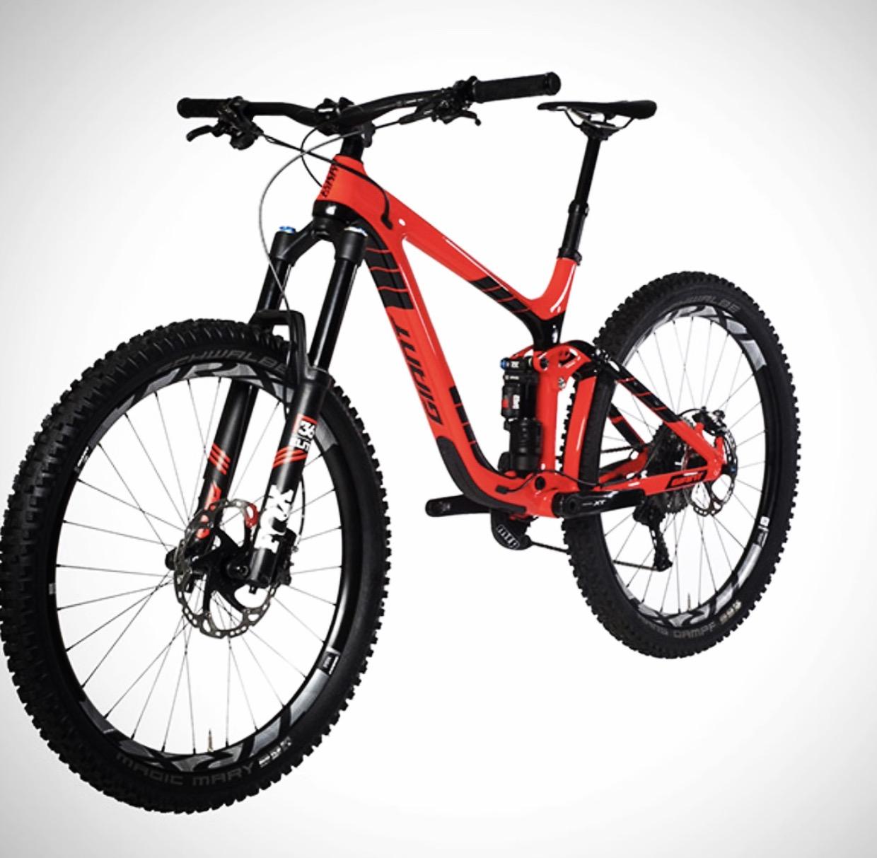 Giant Giant Trance 27.5 2: A red mountain bike with black accents, featuring a dual suspension system, wide tires, and flat handlebars. The bike is positioned at an angle, showcasing its front and side views against a light gradient background.