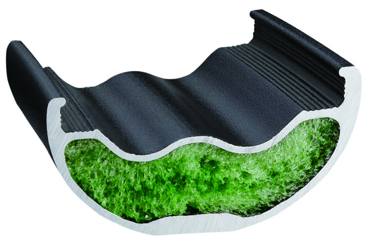 Cross-sectional view of a composite material featuring a black exterior and a green interior with a textured, sponge-like appearance, designed to illustrate the structure and composition of insulation or cushioning materials.