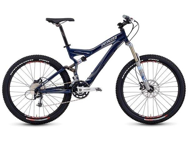 Specialized Stumpjumper FSR Elite: A blue Specialized mountain bike with dual suspension, featuring wide tires, disc brakes, and a gear shifter. The bike is designed for off-road terrain, showcasing a sleek frame and high-performance components.