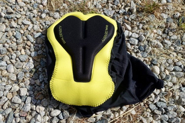 Close-up of a yellow and black padded cycling short laid on a gravel surface. The padding indicates dual density for comfort and support during cycling activities.