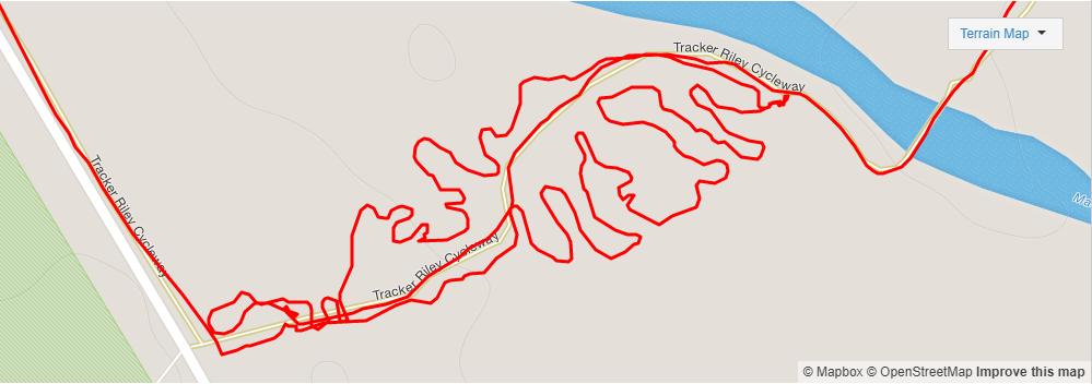 Map showing the route of the Tracker Riley Cycleway, outlined in red, featuring a winding path along a river. The map includes labels for the cycleway and surrounding areas, with a light-colored background indicating terrain. Dundullimal MTB Trail mountain bike trail.