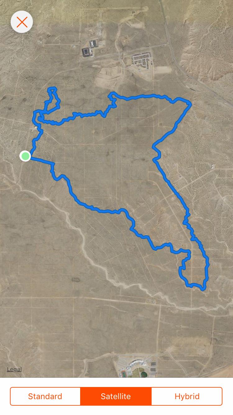 Map showing a trail path outlined in blue through a desert landscape, with a green marker indicating the starting point. The surrounding area includes various terrain features, with some structures visible in the upper portion of the image. Super Fat Bike Loop mountain bike trail.