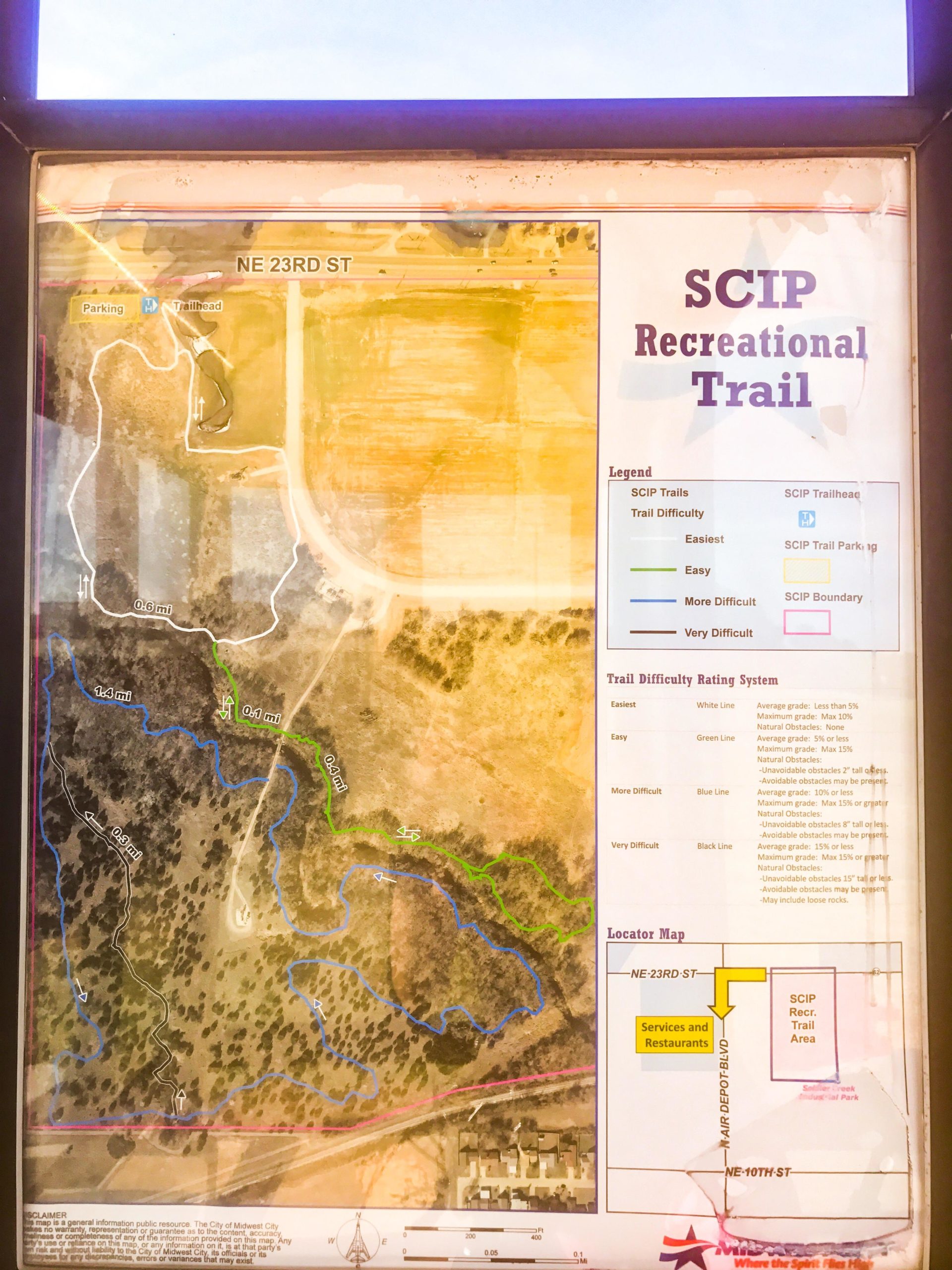 Map of the SCIP Recreational Trail, featuring trail routes and difficulty ratings. The map includes markers for trailhead locations, parking, and nearby streets (NE 23rd St and NE 10th St). Different trail segments are color-coded to indicate difficulty levels: easiest (white), easy (green), more difficult (blue), and very difficult (black). Additional information about trail length and natural obstacles is provided. SCIP Recreational Trail mountain bike trail.