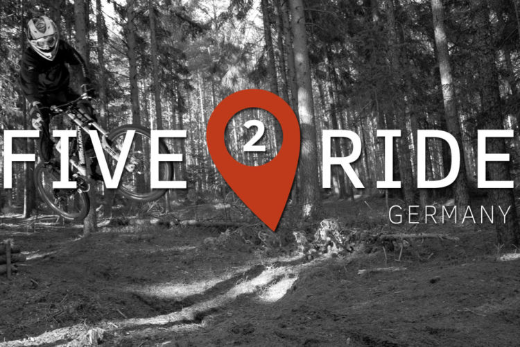A mountain biker performing a jump in a forested area, with the text "FIVE 2 RIDE GERMANY" overlayed on the image, featuring a location pin symbol for emphasis.