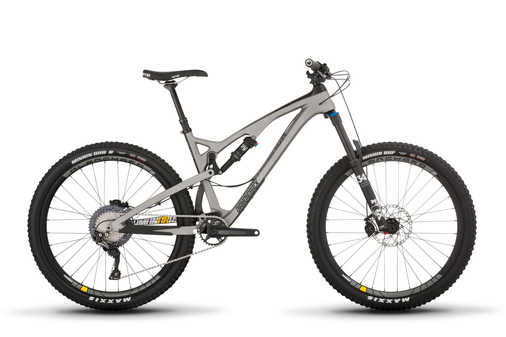 Diamondback Release Carbon: A sleek mountain bike with a gray frame, featuring a prominent suspension system, thick tires, and a modern design. The bike has front and rear disc brakes, a wide handlebars, and is positioned against a white background.