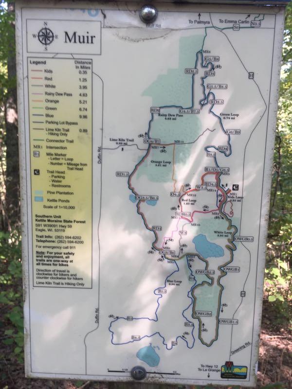 Map of Muir area, detailing hiking trails with color-coded paths (red, orange, blue, etc.), distances, and key landmarks. The legend provides information on trail types and their respective lengths, while the map highlights the surrounding features, including kettle ponds and forest areas. Scale indicates the distance representation is 1 inch to 10,000 inches. John Muir Trails mountain bike trail.