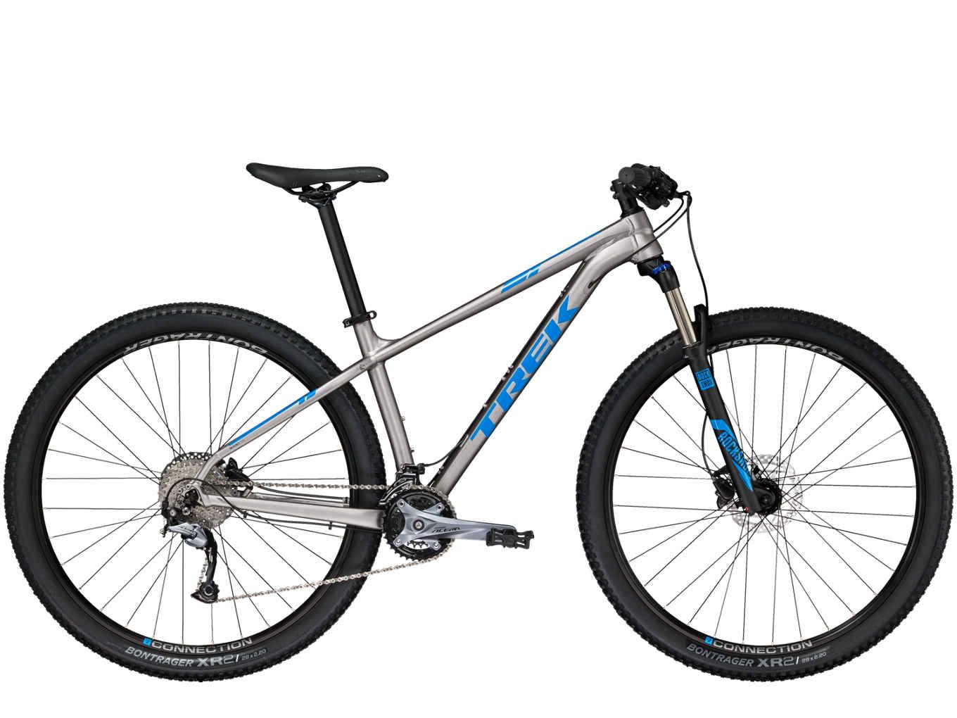 Trek X-Caliber 7: Mountain bike with a silver frame and blue accents, featuring front suspension, wide tires, and a single gear drivetrain.