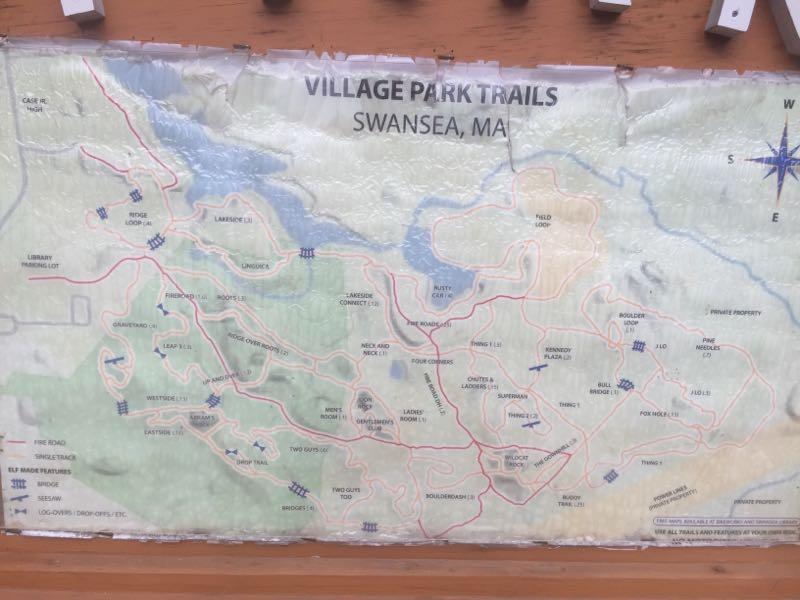 Map of Village Park Trails in Swansea, MA, showing various trail routes and notable features such as libraries, parking lots, and private properties. The map includes a legend and compass rose indicating directions. Village Park/ Abrams Rock mountain bike trail.